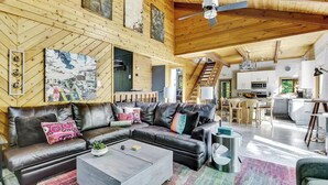 A spacious living area with a leather sofa, a coffee table, and a staircase leading to a kitchen.