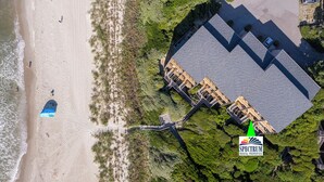 An aerial view of a beachfront property with a large building, a beach, and a pier.
