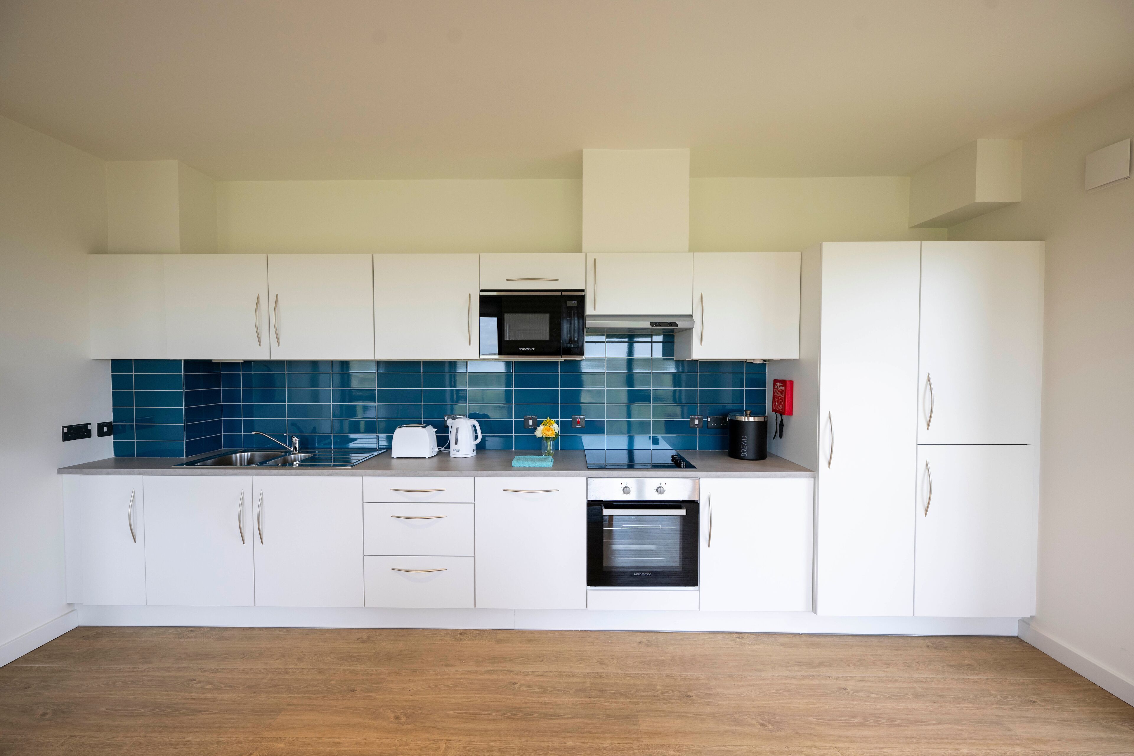 A modern kitchen with white cabinets, a microwave, an oven, and a sink.