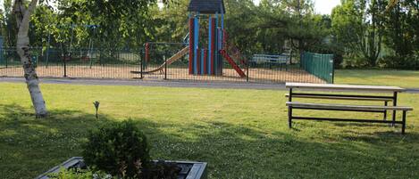 A park with a playground, a picnic table, and a planter box.