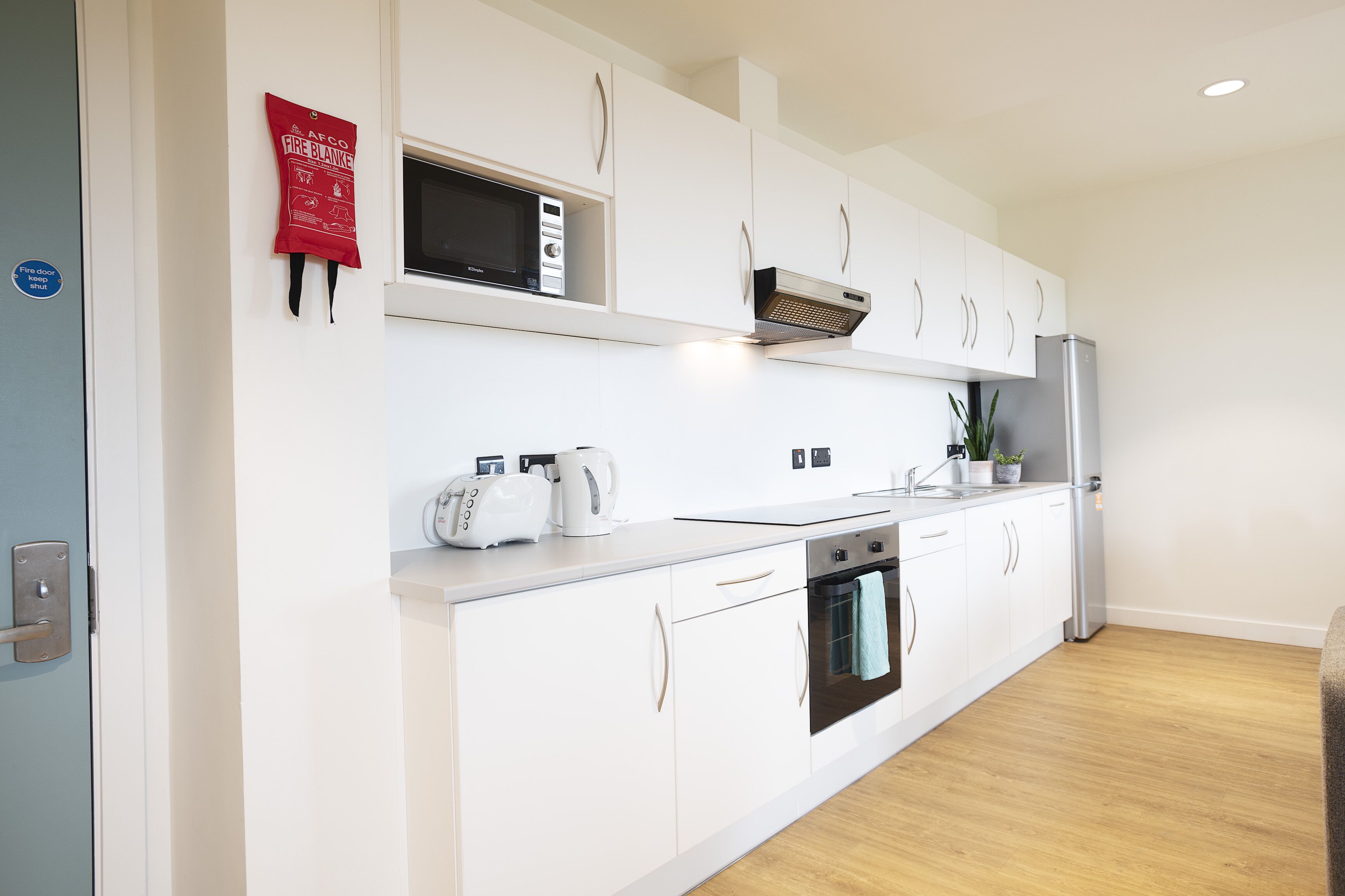 A modern kitchen with white cabinets, a microwave, a toaster, and a stainless steel refrigerator.