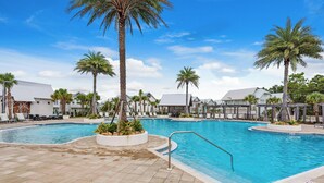 A swimming pool with palm trees, lounge chairs, and a tiled deck.