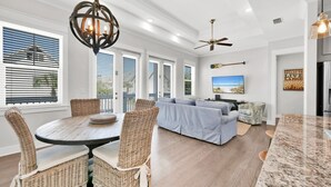 A spacious living room with a large sofa, a dining area with wicker chairs, and a kitchen with a granite countertop.