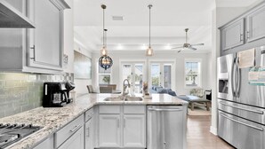 A modern kitchen with granite countertops, stainless steel appliances, and pendant lighting.