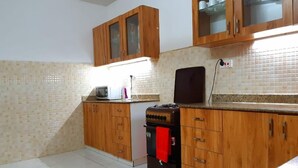 A kitchen with wooden cabinets, a microwave, a stove, and a tiled backsplash. - Mombasa County (Mombasa)