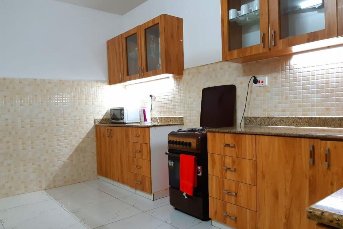 A kitchen with wooden cabinets, a microwave, a stove, and a tiled backsplash.