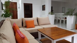 A modern living room with a beige sectional sofa, a wooden coffee table, and a white dining area with a white table and chairs. - Mombasa County (Mombasa)