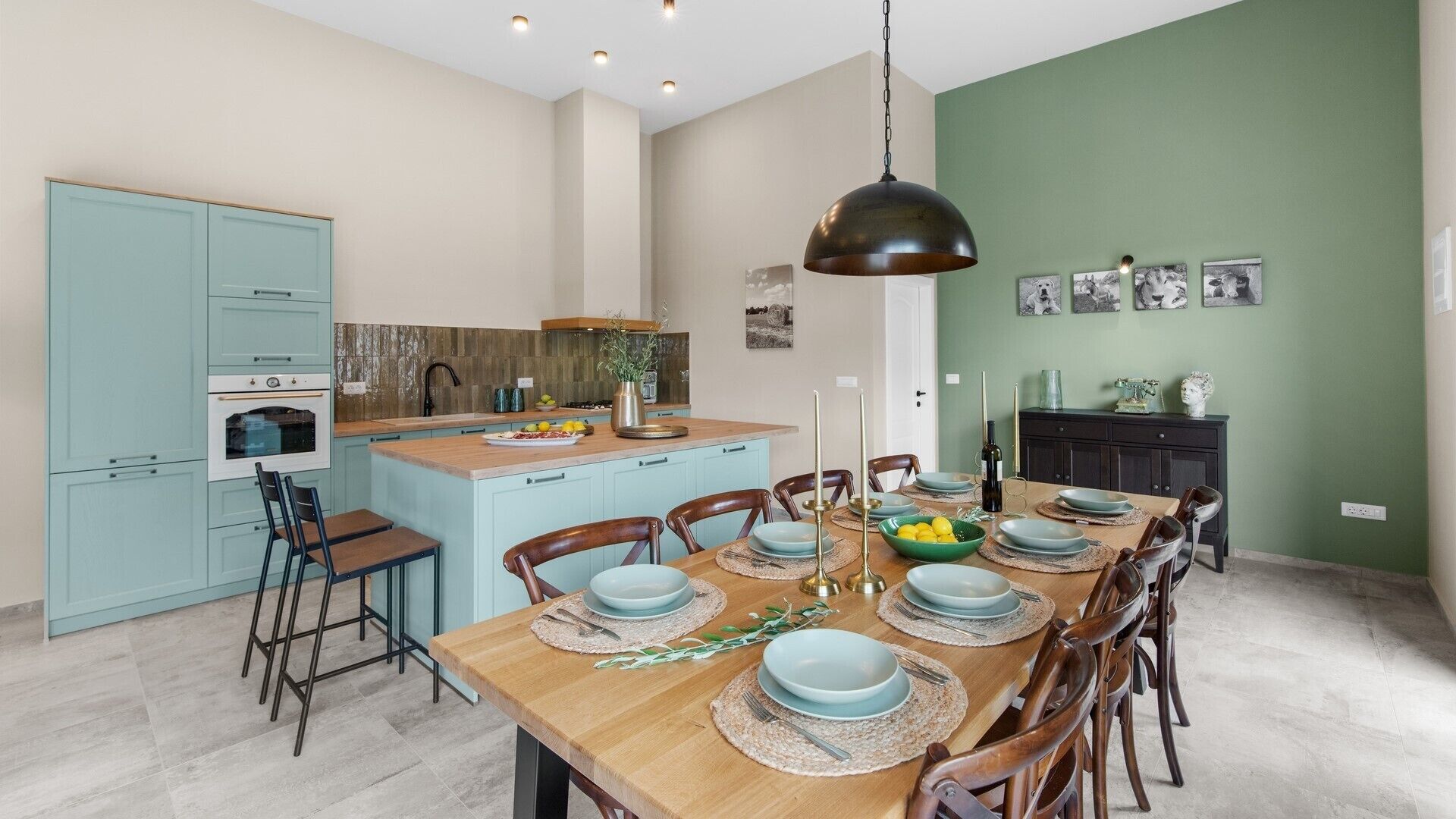 A modern kitchen with light blue cabinets, a central island, and a dining area with a wooden table set for six.