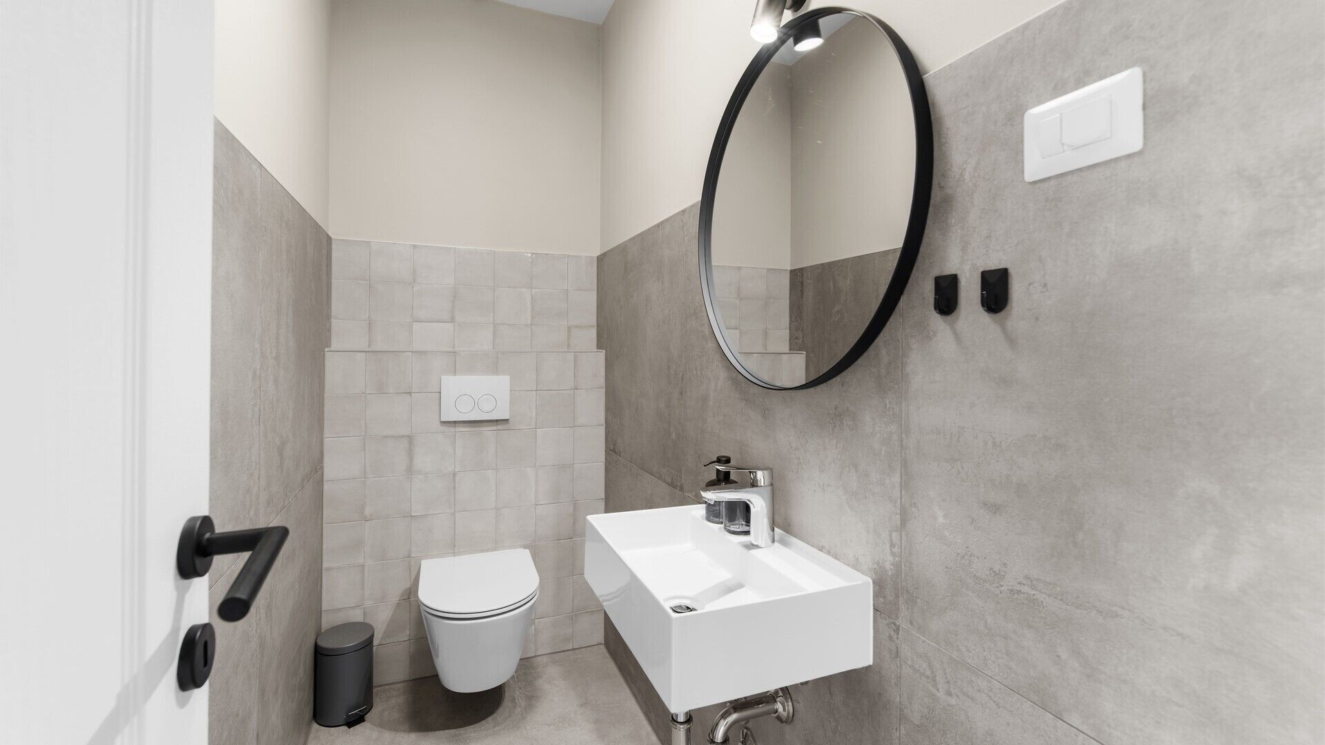 Et moderne badeværelse med toilet, vask og spejl.
