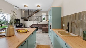 Una cocina moderna con encimera de madera, un lavamanos y una escalera que lleva a un nivel superior.