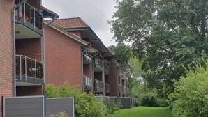 Een meerlaags woongebouw met een bakstenen gevel, balkons en een verzorgd gazon.