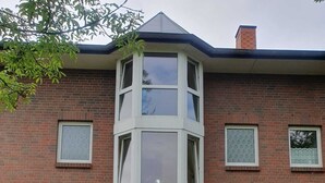 Een hoekpand met een bakstenen gevel, meerdere ramen en een centrale ingang met een deur.