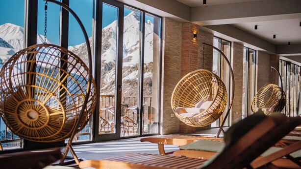 Una habitación con ventanas amplias, sillas de mimbre y una mesa de madera.