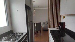 Une cuisine moderne équipée d’une cuisinière à gaz, de plans de travail noirs et d’un coin repas avec un canapé et une table.