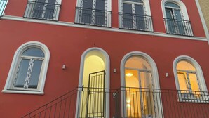 Un immeuble à plusieurs étages, doté d’une façade rouge, de bordures blanches et de balcons avec des garde-corps en métal.