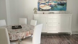 Un coin repas avec une table dressée pour quatre personnes, un meuble blanc avec des tiroirs et un sol à motifs.