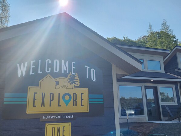 A building with a sign that reads "WELCOME TO EXPLORE" and "MUNISING ALGER FALLS" on the side. - EXPLORE Munising Studio Suite 104 (Munising)