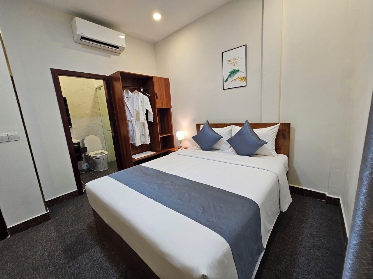 Una habitación de hotel con cama, armario, baño y aire acondicionado de pared.