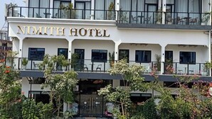 Ein zweistöckiges Hotel mit einem gut sichtbaren Schild mit der Aufschrift 'NIMITH HOTEL'.