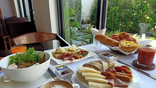 Ein Frühstückstisch mit verschiedenen Speisen, darunter Eier, Toast und ein Salat, sowie eine Tasse Kaffee.