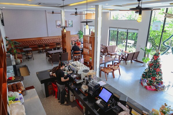 A modern cafe with a central seating area, a coffee machine, and a Christmas tree.