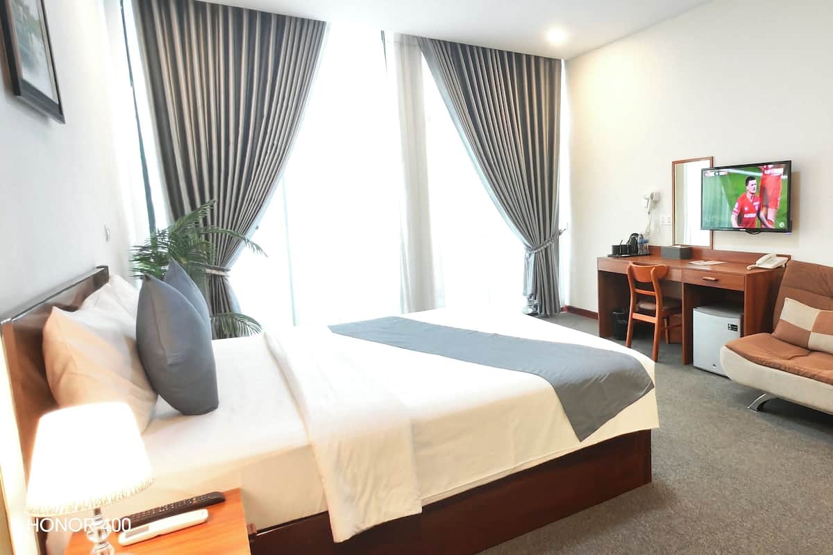 Una habitación de hotel con cama, sofá, escritorio y televisor.