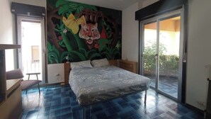 Un dormitori amb un llit, un ventilador de sostre, un mural de tigre i una porta corredissa de vidre cap a l'exterior.