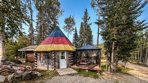 A rustic cabin with a colorful conical roof, surrounded by a forest. - Auberge du Vieux Moulin (Sainte-Emelie-de-L'Energie)