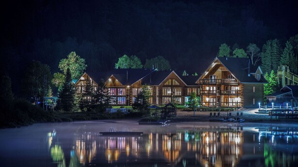 A lodge with multiple wooden cabins, a dock, and a calm lake at night. - Auberge du Vieux Moulin (Sainte-Emelie-de-L'Energie)