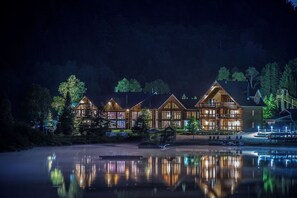Un chalet doté de plusieurs cabanes en bois, d’un quai et d’un lac paisible la nuit.