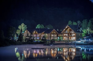 A lodge with multiple wooden cabins, a dock, and a calm lake at night.