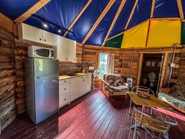 A compact kitchen with a refrigerator, microwave, and wooden cabinets.