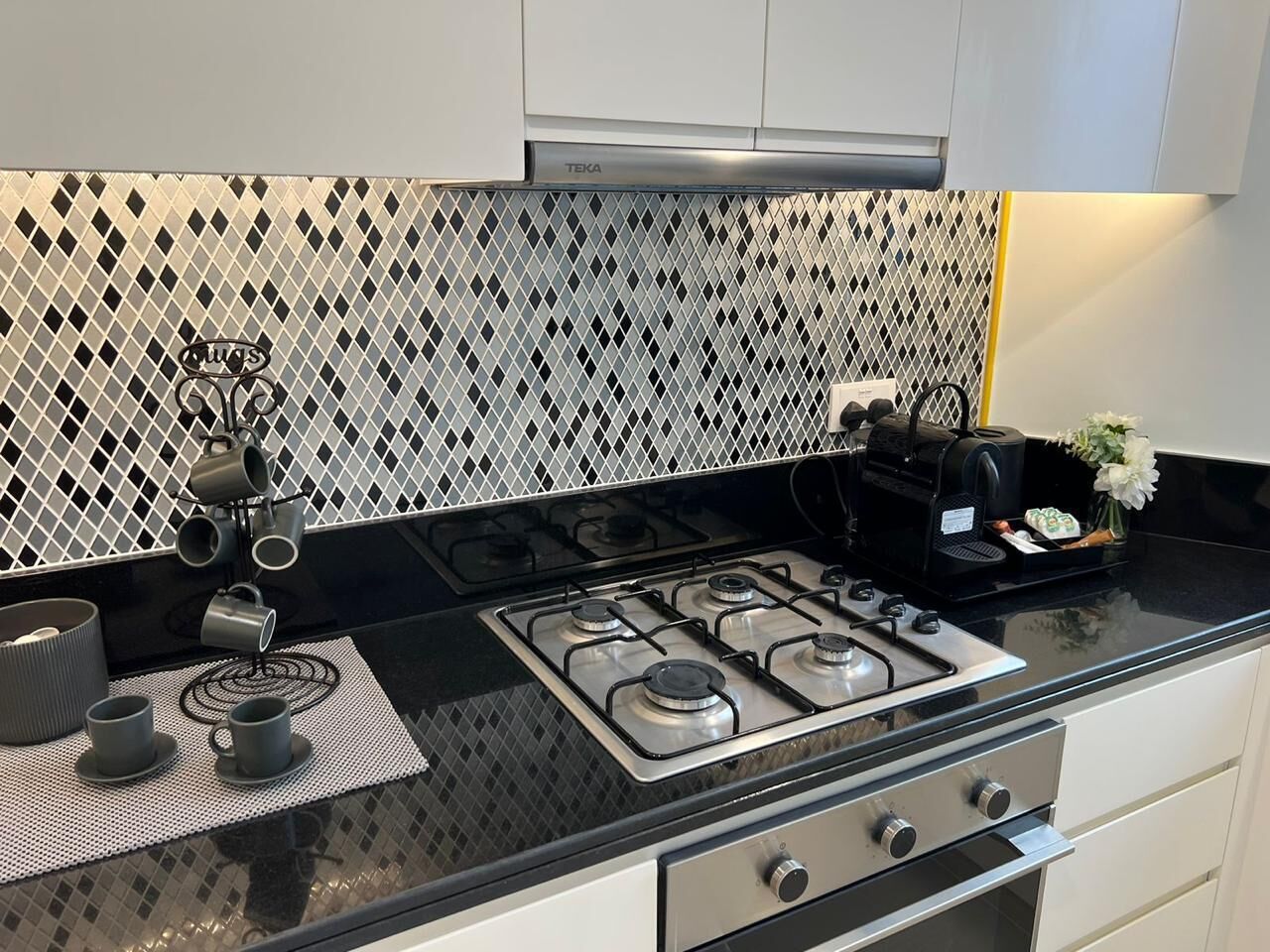 Una cocina con estufa a gas, cafetera y juego de té sobre la encimera.