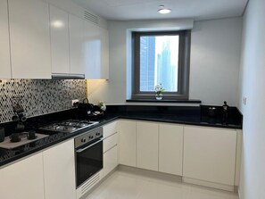 A modern kitchen with a black countertop, white cabinets, and a window with a city view.