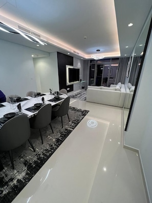 A modern dining area with a long table, chairs, and a television.