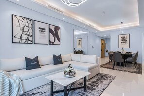 A modern living room with a white sofa, black cushions, and abstract art on the wall. - Stunning Burj Khalifa View Apartment in Downtown (Dubai)
