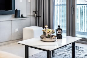 A modern living room with a marble coffee table, a white sofa, a decorative bowl with flowers, and a statue.