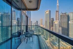 A balcony with a view of a cityscape, including high-rise buildings and a construction crane.