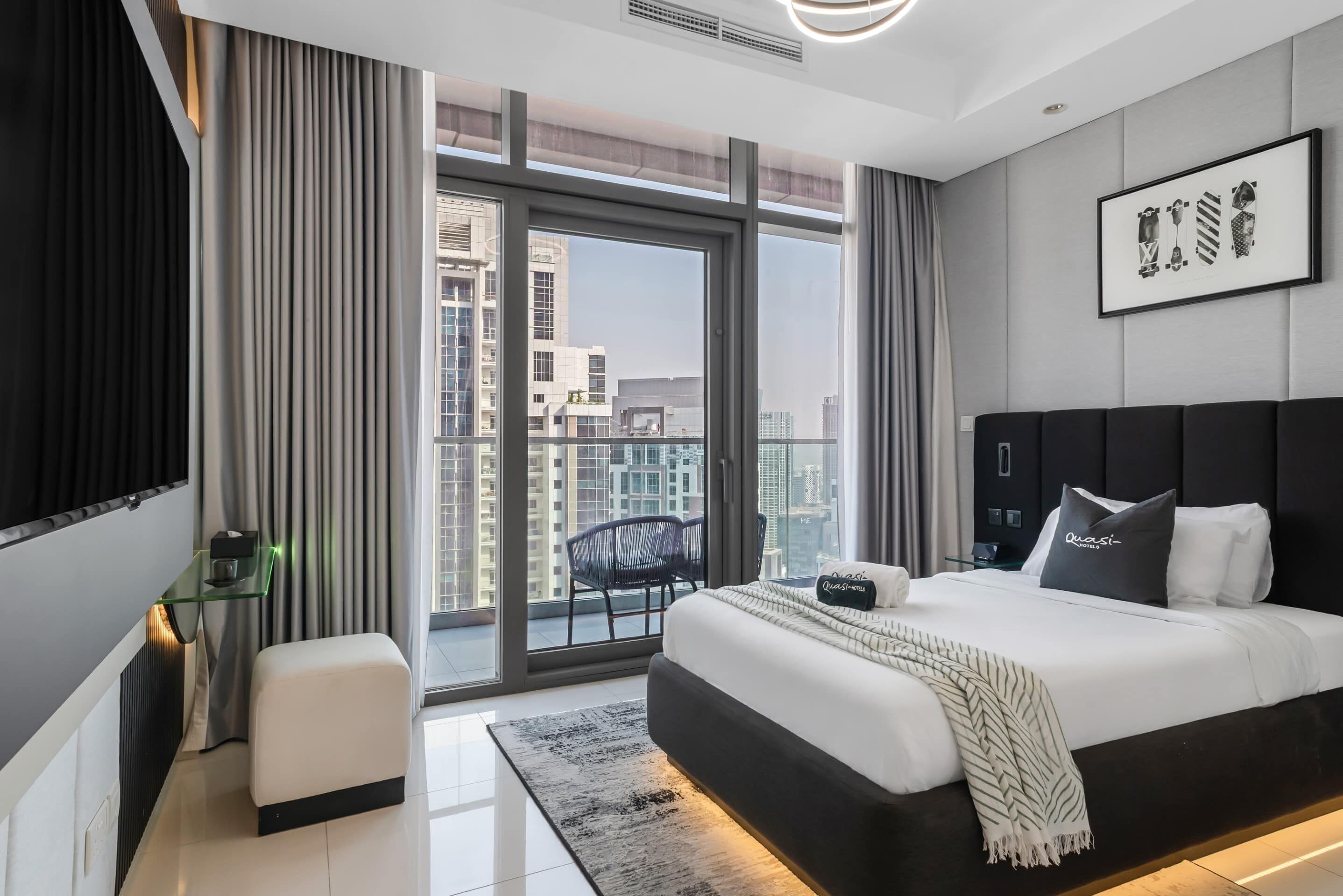 Une chambre d’hôtel moderne avec un grand lit, un bureau, une chaise et une vue sur le paysage urbain.