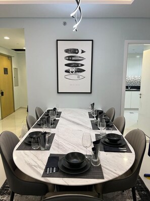 A modern dining area with a marble table, black plates, and clear glasses. - Stunning Burj Khalifa View Apartment in Downtown (Dubai)