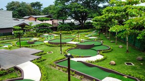 A miniature golf course with multiple holes, surrounded by manicured lawns and trees. - 4BR Private Pool Villa in Jacó | Ciudad del Mar #158 (Jacó)
