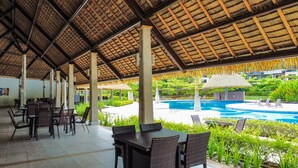 An outdoor seating area with tables and chairs, a pool, and lush greenery. - 4BR Private Pool Villa in Jacó | Ciudad del Mar #158 (Jacó)
