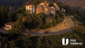 A hillside village with traditional architecture, a winding road, and a view of the surrounding hills. - The Lime Tree (Castiglion Ubertini)