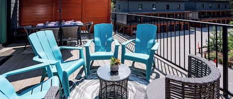 Eine Terrasse mit blauen Stühlen, einem Tisch und einem blauen Sonnenschirm.