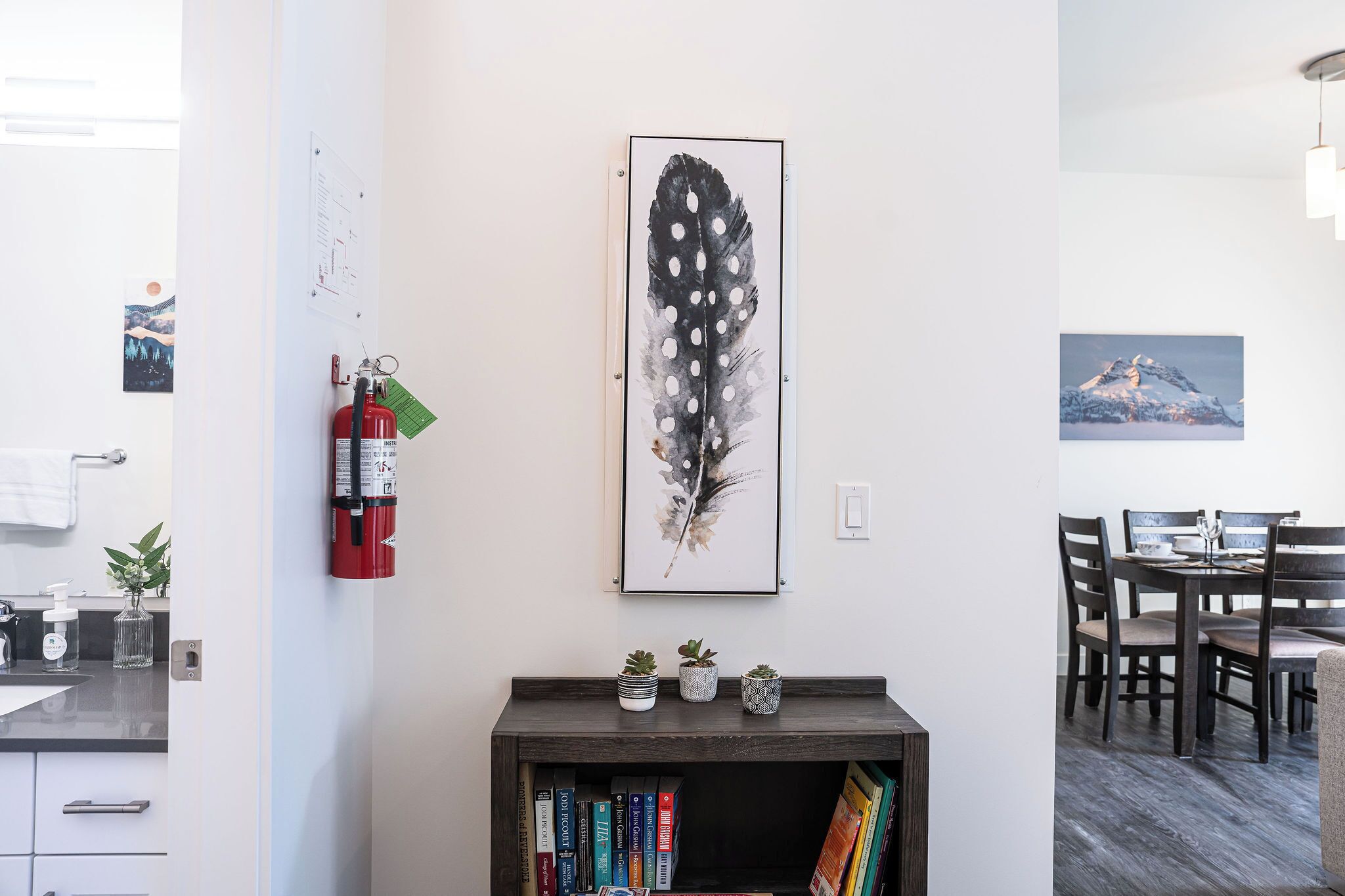 Una cocina moderna con encimera de madera, un extintor y una obra de arte con plumas en la pared.