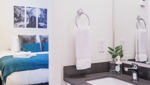 Una habitación de hotel moderna con una cama, un baño con un lavamanos y un espejo.