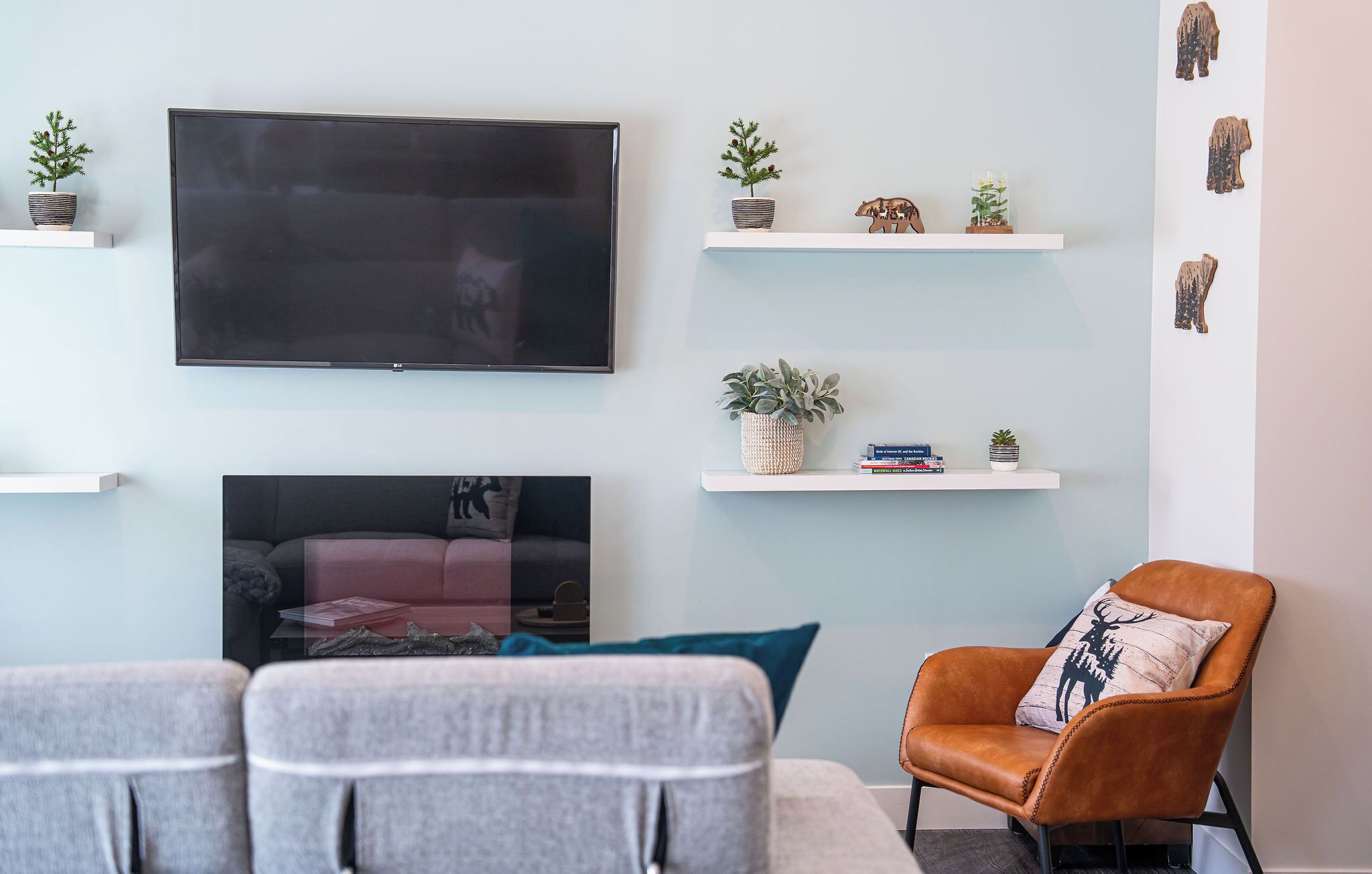 A modern living room with a flat-screen TV, a fireplace, and a leather armchair.