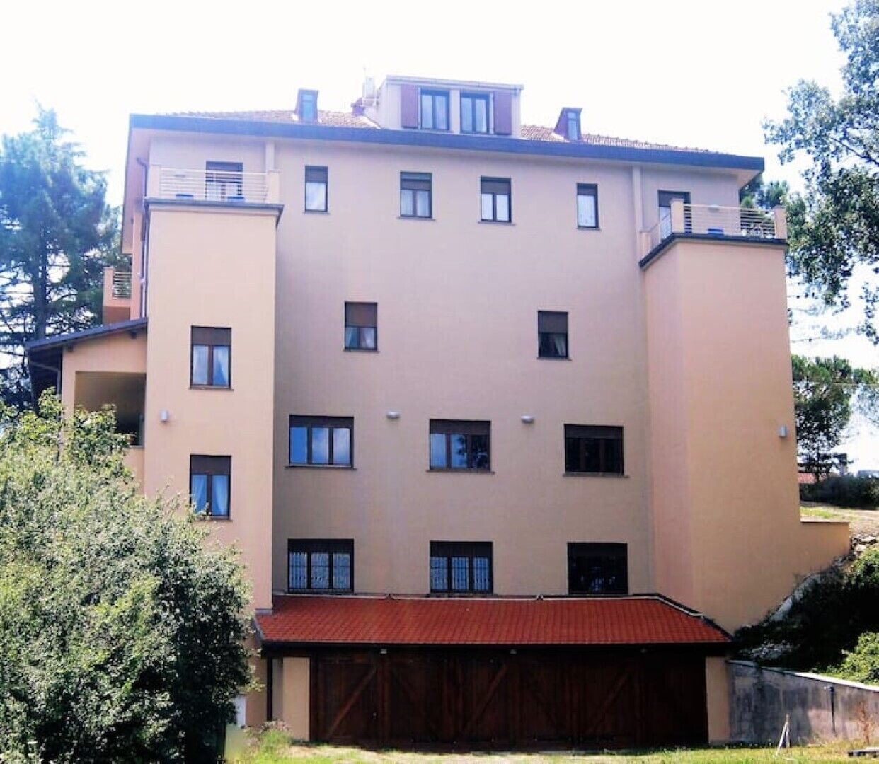 A multi-story residential building with a flat facade, multiple windows, and a red-roofed garage.
