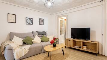 Un salon moderne avec un canapé gris, une table basse en bois et un téléviseur posé sur un meuble en bois.