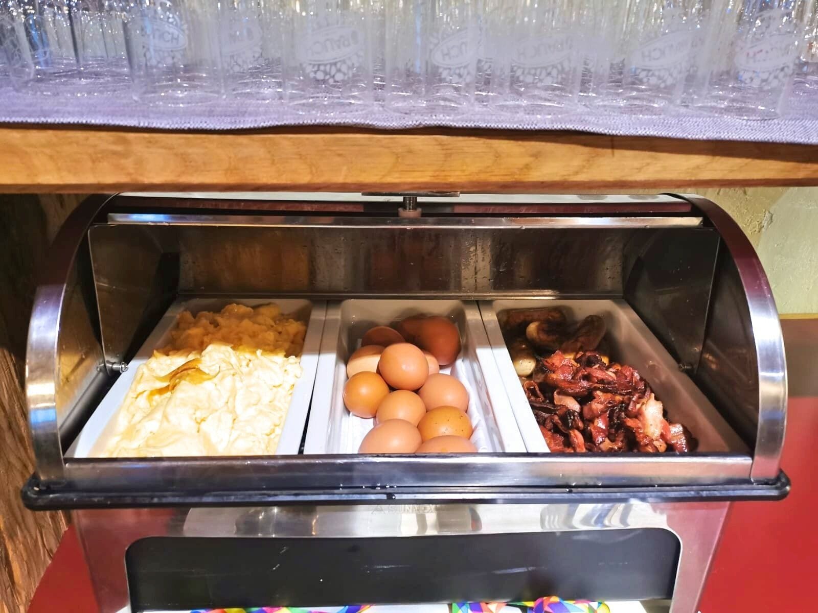 Un buffet proposant des œufs brouillés, des œufs et du bacon.